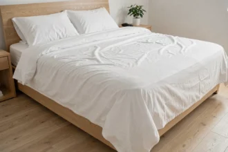 Draps blancs légèrement froissés sur un lit bien fait dans une chambre moderne minimaliste