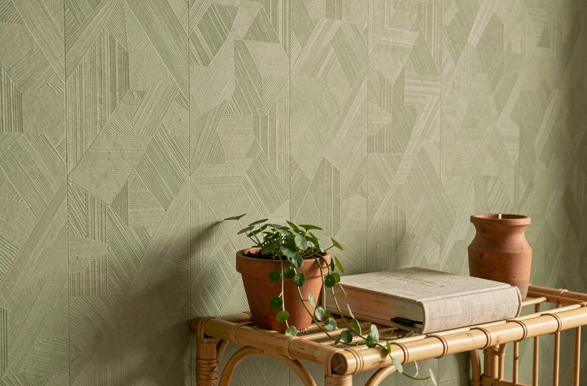 Mur accent recouvert de papier peint texturé vert sauge avec étagère en rotin et plantes en pot