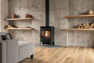 Poêle à bois moderne en fonte noire intégré dans un salon contemporain avec mur en béton brut et parquet chêne clair