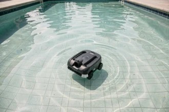 Robot nettoyeur de piscine autonome glissant sur le fond carrelé d'une piscine résidentielle aux eaux limpides, vue de dessus